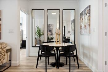 a dining room with black chairs and a table and mirrors on the wall